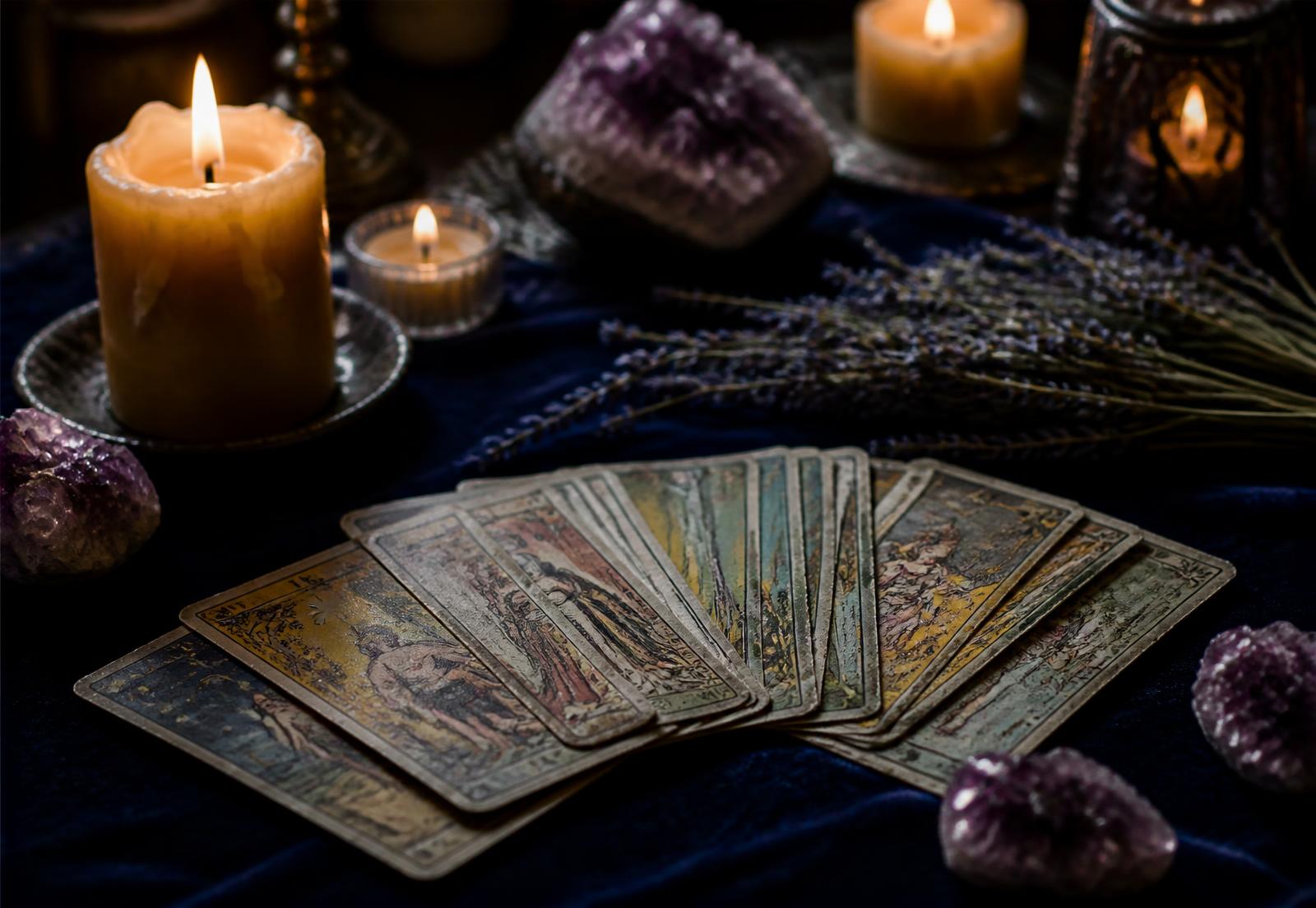 Tarot cards fanned out by candlelight on midnight blue velvet with amethyst and lavender